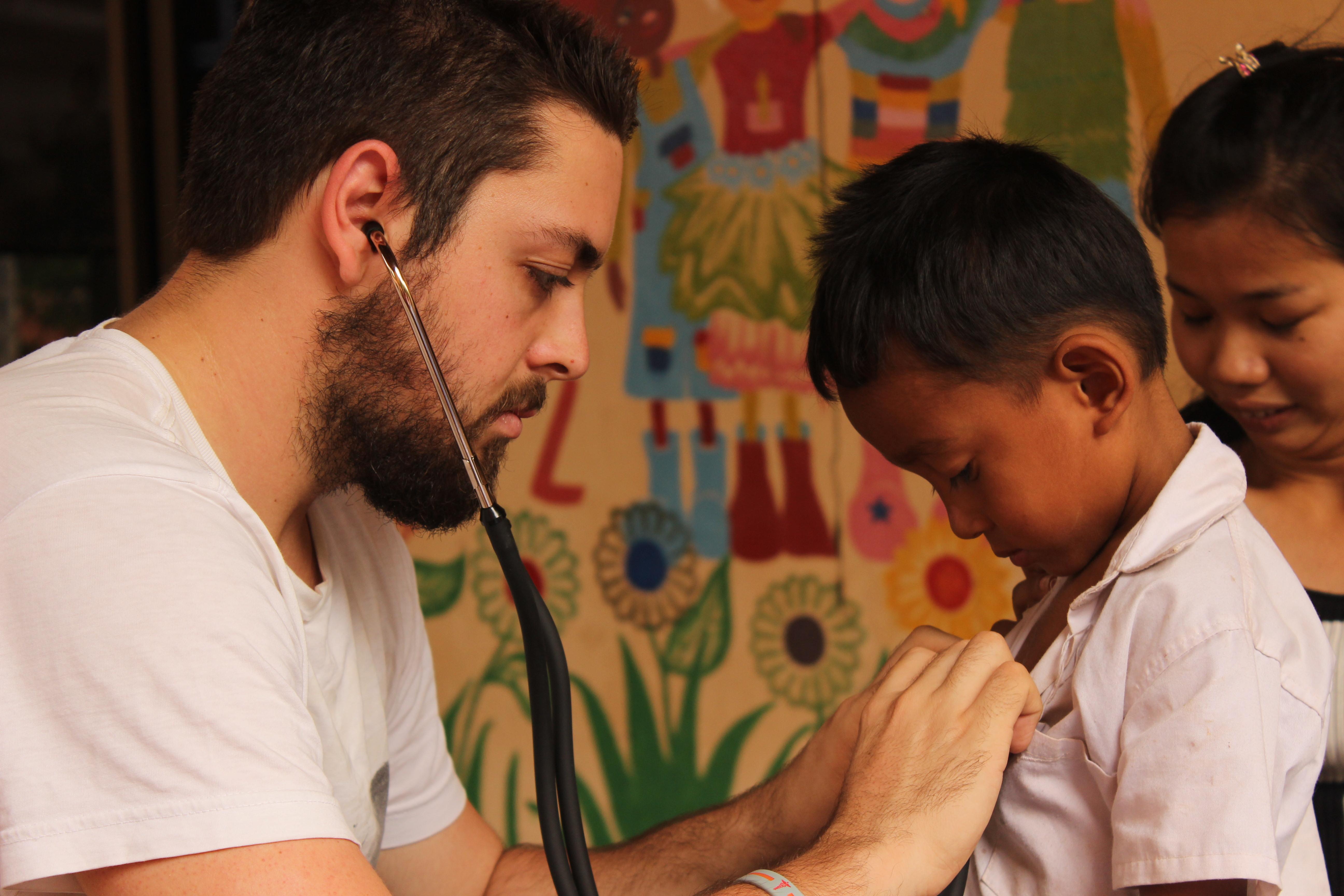 Médico pasante en Camboya realizando un chequeo médico a un niño durante una brigada. Niño es examinado por nuestro pasante médico en Camboya.